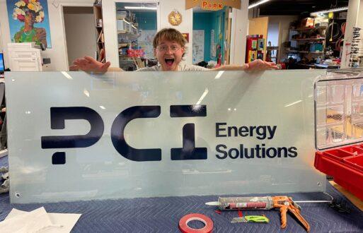 A student worker at the Innovation Hub's Fabrication Lab shows off PCI Energy Solutions' new logo.