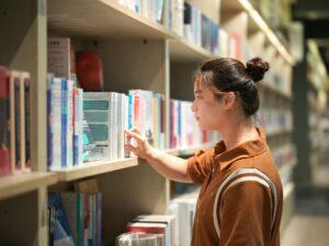 person selecting book from shelf